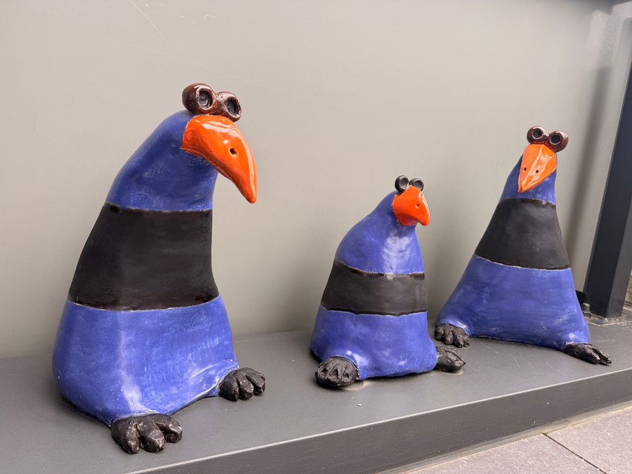 Drie blauwe keramische vogels met oranje snavels